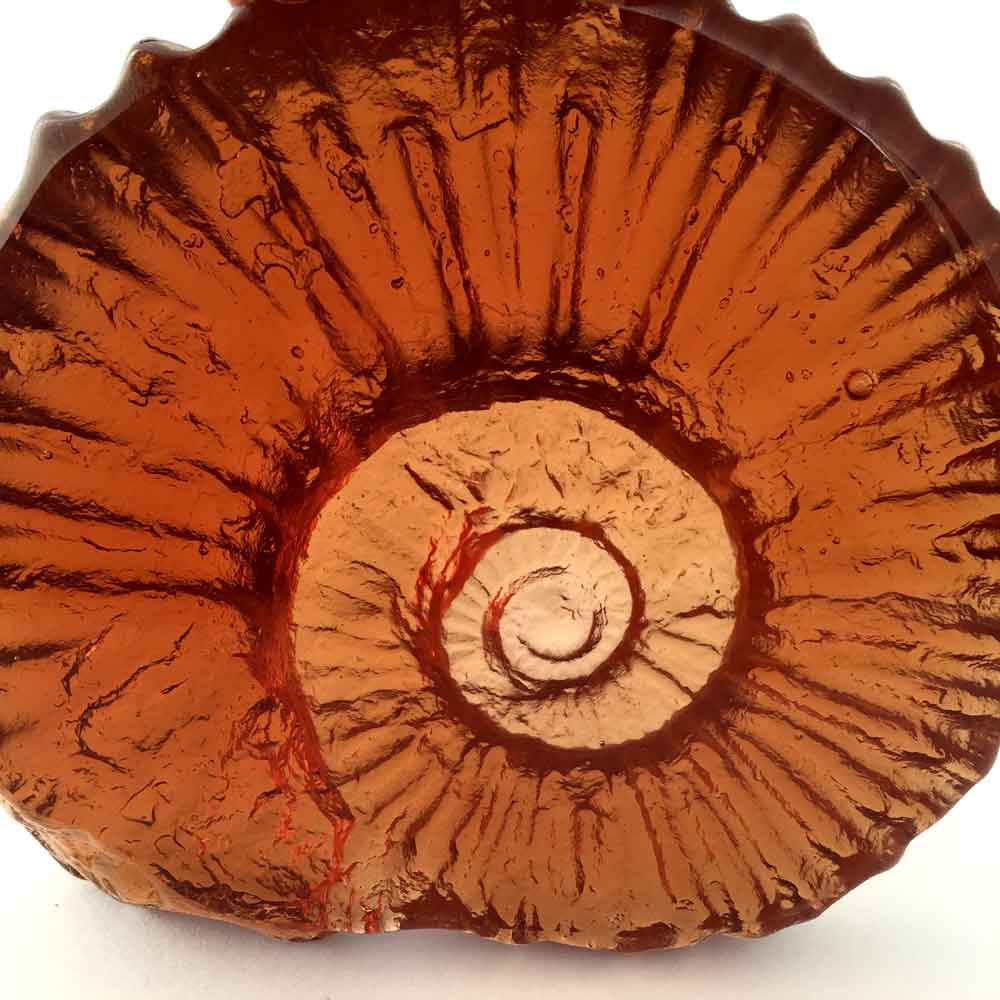 cast glass sculpture of ammonite fossil in orange colour